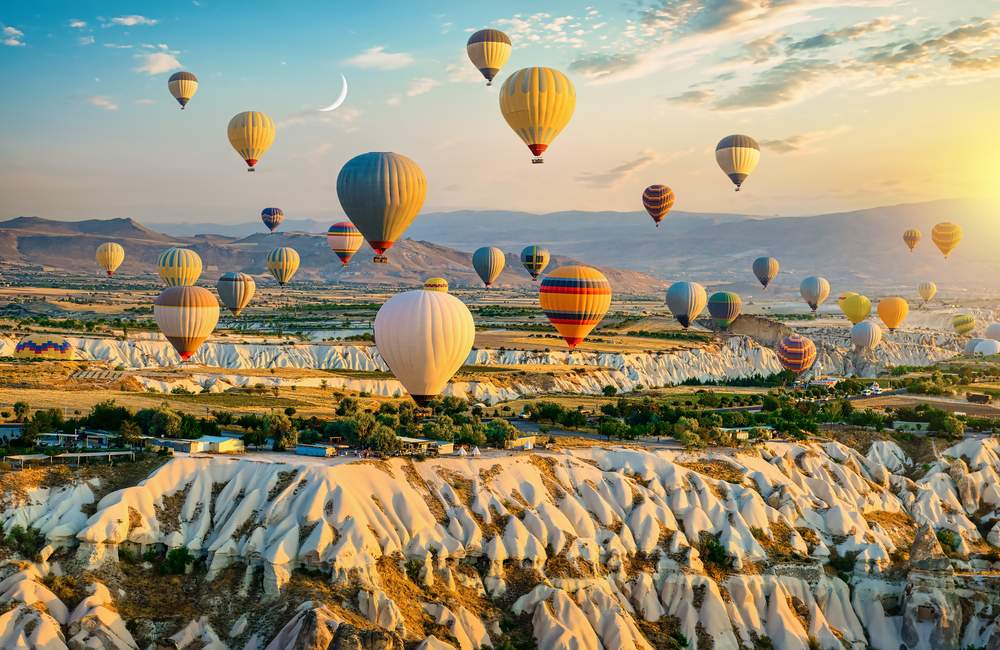 Best viewed at sunrise when dozens of hot air balloons lift over Göreme Valley, depending on seasonal wind conditions.